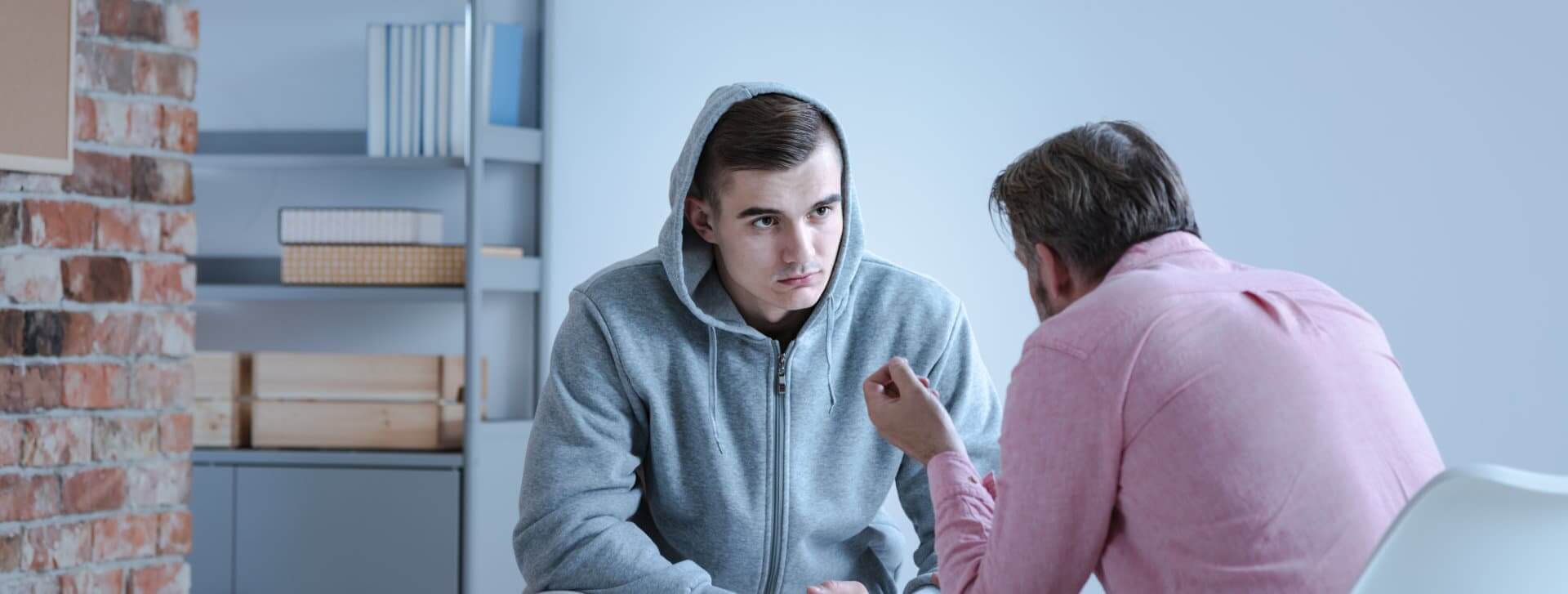 A psychology specialist explaining an action plan for recovery to a troubled teenage boy during an individual therapy session